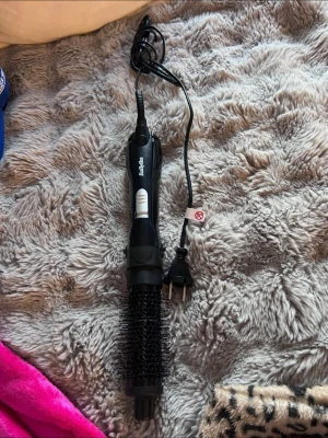 BaByliss svart varmluftsborste - Säljer en svart varmluftsborste från BaByliss med rund borste och sladd med EU-kontakt. Perfekt för att styla håret och skapa volym. Borsten har silverfärgade knappar och är tillverkad i plast och metall.