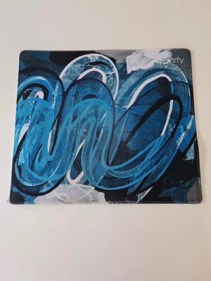 Xtrfy GP4 musmatta Large Blå - I en serie oljemålningar har den svenska konstnären Kim Berkhuizen gjort abstrakt konst av de olika färgsättningarna från Xtrfys Project 4. Versionerna Street Blue och Street Pink baseras på Xtrfys färgsättningar Miami Blue och Pink, och är inspirerade av storstadsliv och färgstark grafitti. Xtrfy GP4 är gjord av slitstarka material och har sydda kanter för ökad hållbarhet.  Storlek L Bredd 460 mm Djup 400 mm        Gamingmusmatta gaming musmatta spel