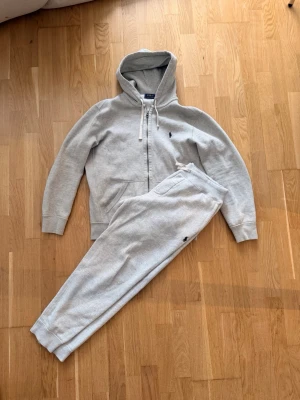 Mjukis-set från Polo Ralph Lauren - Orginal så klart ! set från Polo Ralph Lauren med hoodie och matchande byxor. Hoodien har dragkedja, fickor och justerbar huva med snören. Byxorna har resår i midjan och muddar vid benslut. Båda plaggen har den klassiska Polo-loggan broderad. Storlek M tröja storlek M byxa och snälla be mig inte skicka bilder med kläderna på dom passar ej längre