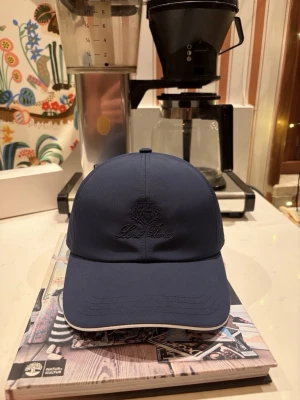  keps från Loro piana - Stilren mörkblå keps från Lord Pine med broderad logga framtill och en liten metallbricka på sidan. Kepsen är i modellen ”storm system” av LP. Kepsen är i nytt skick och är endast testad. Pris 499 har ni frågor är det ba att fråga.  