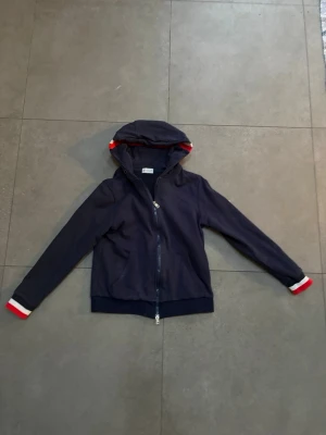 Moncler Hoodie - Här har vi en på tok för liten Moncler hoodie. Den har storlek 3 vilket motsvarar M. Vettefan om det är en medium dock, då den sitter tajt som bara den. Bytte en av mina svarta Arcteryx jacker emot den så har ingen aning om den är ekta eller inte. (Skulle inte gissa på det). Inte använd av mig en enda gång förutom när jag testat den. En tidigare ägare. Priset kan såklart diskuteras, och om ni vill ha fler bilder eller har några frågor är det bara att skriva!! 