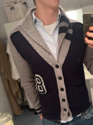 Mörkblå stickad tröja från Replay - Snygg mörkblå stickad tröja från Replay med detaljer i ljusgrått. Tröjan är handgjord och har en klassisk passform. Perfekt för dig som gillar stilrena och tidlösa plagg. Materialet känns mjukt och håller värmen bra.