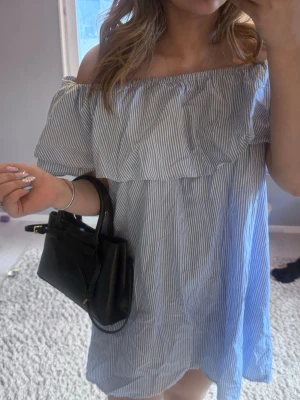 Randig offshoulder sommarklänning - Söt kort offshoulder klänning med blåvita ränder och volang upptill. Perfekt för varma dagar och har en avslappnad passform. Tillverkad i lätt bomullsmaterial som känns skönt mot huden.
