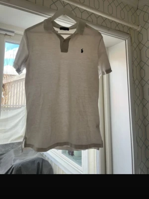 Vit piké från Ralph Lauren - Vit pikétröja från Ralph Lauren med klassisk krage i vit och korta ärmar. Tröjan har några små svanker som fläckarna på den som syns k bilderna 