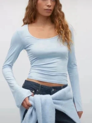 Ljusblå långärmad topp - En ljusblå långärmad topp med rundad halsringning och figurnära passform. Toppen är enkel och stilren, perfekt att matcha med jeans eller kjol. Materialet känns mjukt och stretchigt för en bekväm känsla. Har knappt använt 