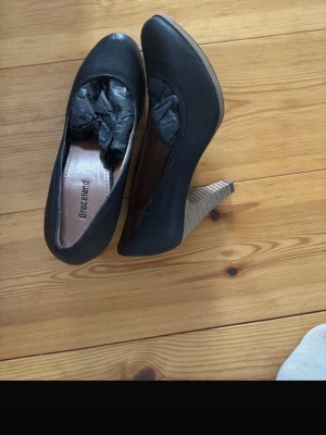 Svarta pumps från Graceland - Snygga svarta pumps från Graceland med rund tå och stabil klack i trälook. Skorna har en klassisk design och är tillverkade i ett matt material som ger en stilren känsla. Perfekta för dig som vill ha en tidlös och enkel sko med lite höjd.