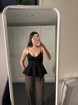 Svart peplum linnetopp Gina Tricot - Säljer en svart peplum linnetopp från Gina Tricot. Toppen har tunna axelband, djup v-ringning och en volang nedtill som ger en snygg siluett. Perfekt att styla med jeans eller kjol.