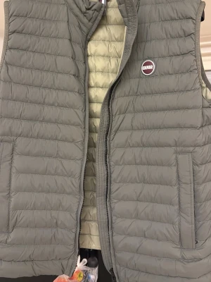 Grå dunväst från Colmar - Snygg grå dunväst från Colmar. Perfekt att slänga över en hoodie eller tröja när det är kyligt ute. Använd 2 gånger så den är som ny!