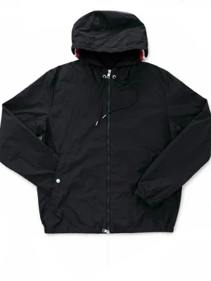 Svart Moncler vindjacka med huva - Snygg svart Moncler vindjacka med dragkedja och justerbar huva. Jackan har vita och röda detaljer på insidan av huvan och är tillverkad i ett lätt, vattentät material. Perfekt för blåsiga dagar och enkel att matcha med olika outfits.