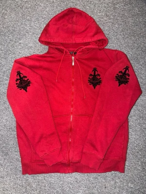 Röd hoodie med svarta tryck - Röd hoodie från Dan Ryan med dragkedja, huva och snörning. Hör av dig vid frågor och funderingar!🤗