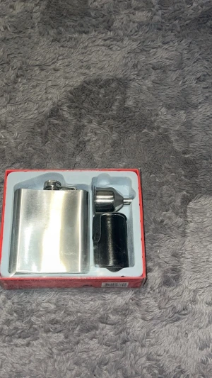  Fickplunta i Rostfritt Stål – Presentkit - Ett stilrent och komplett set med en klassisk fickplunta i rostfritt stål. Innehåller även en praktisk tratt för enkel påfyllning och två eleganta små muggar med läderfodral. Perfekt som present eller för friluftsäventyret. • Skick: Helt ny i originalförpackning (toppskick).