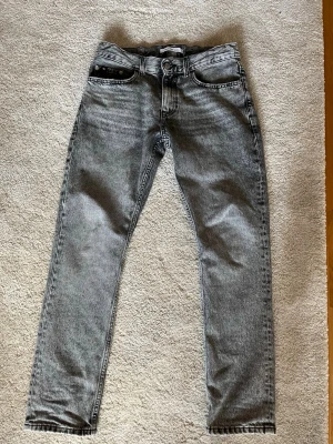 Gråa Calvin Klein jeans  - Snygga gråa jeans från Calvin Klein som är perfekt för dig som vill ha ett par riktigt stil rena jeans till vardags!                                                                Vid frågor och funderingar är det bara att höra av sig!