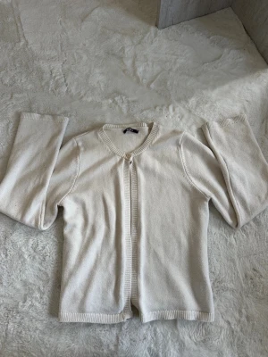 Vit kofta från Gina Tricot - Klassisk vit kofta från Gina Tricot med rund halsringning och ribbade kanter. Koftan har lång ärm och är tillverkad i mjukt stickat material. Perfekt att slänga över en topp för en enkel och clean look. Använd max 2 gånger inga fläckar. Den e som ny pris kan diskuteras 