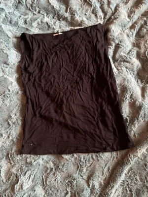 Svart ärmlös linnetopp - En enkel svart linnetopp i mjuk bomull. Toppen är ärmlös och har en rak passform, perfekt att matcha med olika stilar. Storlek 150/157 enligt lappen. Snygg och basic för alla tillfällen.