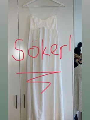 SÖKER!!! - Elegant vit långklänning med tunna axelband och lätt v-ringad överdel. Klänningen har en luftig passform och är perfekt för varma dagar. Tillverkad i ett mjukt och lätt material som ger en skön känsla.