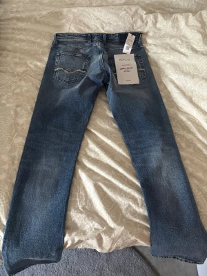 Jeans från Replay - Helt nya !!!! Snygga blå jeans från Replay med slitningar och lätt tvättad look. Storlek w30 L32 , Klassisk femficksmodell med raka ben och detaljerade bakfickor. Jeansen har en modern, avslappnad passform och är tillverkade i bomull. 