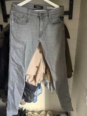 Grå jeans från Replay - Snygga grå jeans från Replay med klassisk femficksdesign och raka ben. Jeansen har svarta detaljer vid fickorna och tydliga sömmar. Perfekta för en avslappnad och trendig stil. Materialet är denim i bomullsblandning.