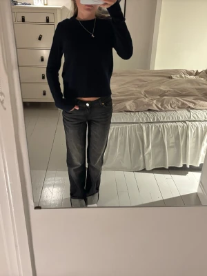 Mörkblå stickad tröja - Mysig mörkblå stickad tröja med rund halsringning och långa ärmar. Tröjan har en enkel och stilren design med ribbstickade muddar vid ärmslut och nederkant. Perfekt att matcha med jeans för en avslappnad look.