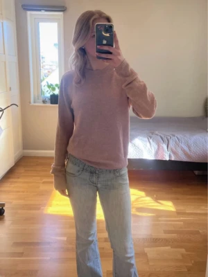 Ljusrosa stickad tröja - Mysig ljusrosa stickad tröja med rund halsringning och långa ärmar. Tröjan har en enkel, klassisk design utan synliga loggor eller mönster och är tillverkad i ett mjukt material som passar perfekt för kyligare dagar.