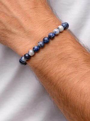Blått pärlarmband i sten - Snyggt armband med runda pärlor i olika nyanser av blått och vitt. Pärlorna är troligen gjorda av sten och sitter på en elastisk tråd, vilket gör det enkelt att ta på och av. Perfekt accessoar för en stilren och avslappnad look.