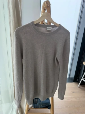 Beige tröja  - En stilren beige tröja från John Henric  med rund halsringning och långa ärmar. Tröjan är tunnstickad och har ribbade muddar vid ärmslut och nederkant. Perfekt för lager-på-lager och enkel att matcha med olika outfits.