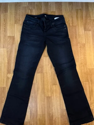 Svarta bootcut jeans från LTB - Snygga svarta bootcut jeans från LTB med klassisk femficksdesign och låg midja. Jeansen har en lätt utsvängd passform nedtill och är tillverkade i mjuk denim med stretch för extra komfort. Perfekta till en avslappnad och trendig look.