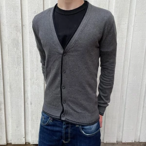 Mörkgrå Bomullscardigan - Simpel men stilig kofta/cardigan i snygg design! | Notera de unika detaljerna vid ärmsluten och längs vissa kanter av plagget! | Hör av dig vid fler frågor!