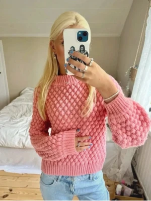 Rosa bubbelstickad tröja - Säljer en rosa stickad tröja med bubbelmönster och rund hals. Tröjan har långa ärmar och ribbade muddar vid hals, ärmslut och nederkant. Perfekt för dig som vill ha något mysigt och trendigt i garderoben.