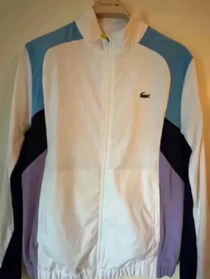 Lacoste vindjacka  - En riktigt snygg vindjacka från Lacoste köpt på nätet för cirka 1 år sen. Jag använder inte den. Den är använd knappt 3 gånger. Den är helt ny och ligger bara nu i garderoben. 