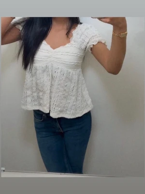 Vit blus med spetsdetaljer - Söt vit blus med v-ringning och korta ärmar. Toppen har spetsdetaljer och volangkant, 
