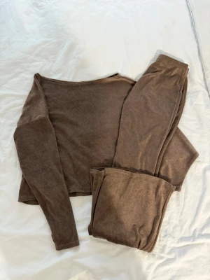 Brunt mjukt loungewear-set - Mysigt loungewear-set i mjukt brunt material med långärmad tröja och matchande byxor. Perfekt för chill dagar hemma. Materialet ser ut att vara stretchigt och bekvämt, med enkel och avslappnad passform.