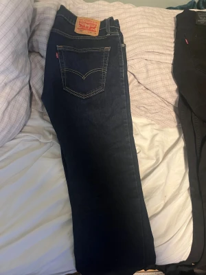 Levi's 502 mörkblå jeans W31 L32 - Säljer ett par klassiska Levi's 502 jeans i mörkblå denim. Modellen har raka ben, fem fickor och tydliga kontrastsömmar. Ikonisk läderpatch bak och röd Levi's-tag på bakfickan. Perfekta för dig som gillar tidlös och enkel stil. Har även ett par 514 mörkblå med storlek 33W 30L