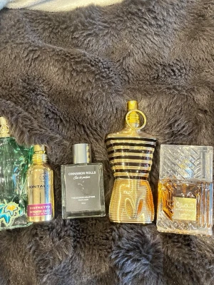 Fem unika parfymer mixade märken - Parfym paket kom Dm om frågor tex hur mycket kvar och pris och sånt Säljer fem olika parfymer: en grön flaska med palmmotiv, Montale Ristretto Intense Café i metallisk guldflaska, Cinnamon Rolls från Theodoros Kalotinis i svart fyrkantig flaska, Jean Paul Gaultier Le Male Le Parfum i guldig kroppsliknande flaska och Lattafa Khamrah i elegant glasflaska med arabiska detaljer.