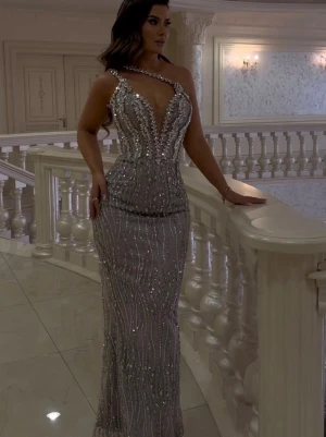 Silver långklänning med paljetter - Elegant långklänning i silver med glittriga paljetter och pärlor. Materialet är troligtvis polyester eller satin, perfekt för speciella tillfällen. Har satt en grå tyg bytt vid bröstet men går o ta bort de om man inte vill ha de. Klänningen är använt endast en gång i 6 timmar bara. Klänningen är beställd från Kosovo. Klänningen kan spenats där back och även en dragkedja lite längre ner. De passar storlek XXS, XS, S även M.  Pris kan diskutera. 