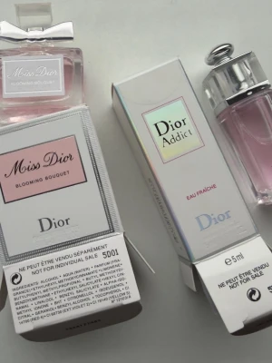 Dior parfym duo: Miss Dior & Addict set - Säljer två exklusiva parfymer från Dior: Miss Dior Blooming Bouquet i en elegant rosa glasflaska med silverdetaljer och rosett, samt Dior Addict Eau Fraîche i en stilren flaska med metallock. Båda kommer i sina originalkartonger och har en feminin, fräsch doft.