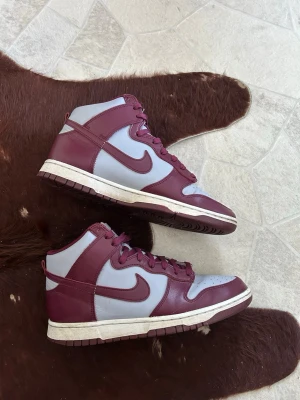 Nike Dunk High Beetroot - Snygga Nike Dunk High i bordeax rött och grått, som heter dark beetroot från 2022, varsamt använda inte mycket slitningar på tex sula. storlek 44 tyvär ingen låda, söker främst byte mot jordan 5 men även jordan 1/2/3/4/6/7/11/12