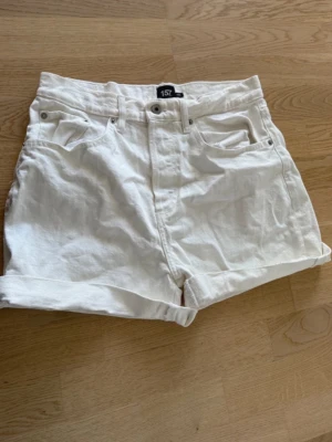 Vita högmidjade shorts i bomull - Snygga vita shorts sopassar perfekt till sommaren. De är högmidjade med klassisk femficksdesign och uppvikta benslut. Gjorda i mjuk bomull för en skön känsla. Perfekta för en avslappnad och trendig look.