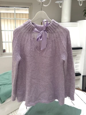 Stickad tröja i mohair-mix - Storlek 40 (L). Material: 30% akryl, 30% polyamid, 30% mohair. Finns enstaka fläckar på rosetten. Skickas inom 24h.