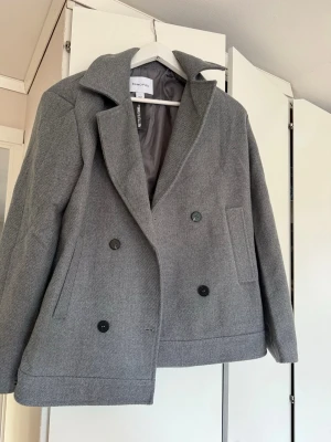 Grå kappa - Grå kappa i storlek 36/S. Aldrig använd, prislappen sitter kvar. Bra kvalité. Den är rak/boxig i passformen.              Ny pris 799kr. 
