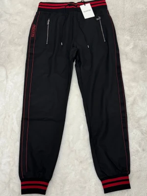 Svarta mjukisbyxor från Valentino - Snygga svarta mjukisbyxor från Valentino med röda detaljer och ränder längs benen. 