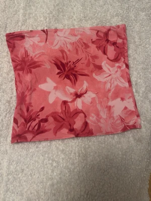 Blommig rosa bandeau tubtopp - Säljer en blommig rosa bandeau tubtopp med stora blommor i olika rosa nyanser. Toppen är ärmlös och har en croppad passform, perfekt för varma dagar. Materialet känns mjukt och stretchigt, vilket gör den bekväm att bära.