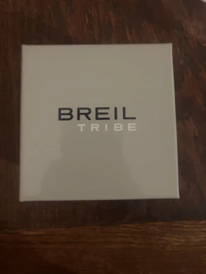 Breil Tribe klocka och certifikat - Säljer en stilren Breil Tribe klocka i ljusgrå färg med glitter runt om, säljer den pågrund av att jag ej gillar klockor så mycket och bär inte på klockor den är helt ny och har behållt den in i asken.