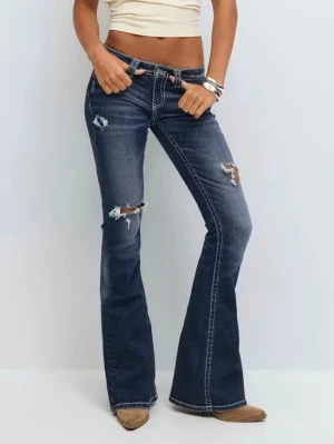 Bootcut jeans med slitningar - Mörkblå bootcut jeans med slitna detaljer och hål på låren. Snygga kontrastsömmar och broderade bakfickor ger extra stil. Klassisk femficksmodell i stretchigt denimtyg som sitter tajt upptill och har utsvängda ben.