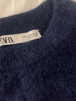 Mörkblå stickad tröja Zara - mörkblå stickad tröja från Zara med fluffig yta och rund halsringning. Säljer på grund av att jag ej använder den, använd några gånger men inga defekter 