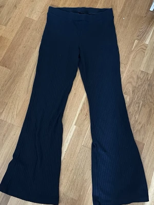Mörkblå  ribbade utsvängda leggings - Snygga mörkblå leggings med ribbad struktur och utsvängda ben. Perfekta för en trendig och bekväm stil. Hög midja och stretchigt material gör dem lätta att bära hela dagen.