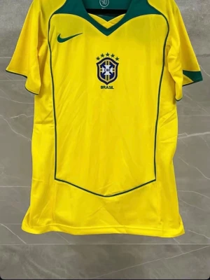 Brasilien Nike fotbollströja - Gul Brasilien fotbollströja från Nike med gröna detaljer och CBF-logga på bröstet. Klassisk V-ringning och korta ärmar, perfekt för fotboll eller träning. Ikonisk design med gröna linjer och Nike-logga.  Finns i olika storlekar!!! Pris kan diskuteras!!!
