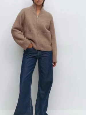 Beige stickad kofta med dragkedja - Mysig beige stickad kofta med hög krage och dragkedja framtill. Koftan har två stora fickor och en avslappnad passform, perfekt att slänga på sig över en t-shirt. Stilren och enkel design som funkar till det mesta.SLUTSÅLD 