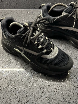 Svarta b22 - Chunky sneakers b22 i svart med vita och grå detaljer. Ovandelen är i mesh och syntet med reflekterande inslag och tjock sula. Skorna har låga skaft och sportig design med snörning och dragflik bak. Passar även storlek 44/44,5 box följs även med!