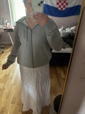 Vit långkjol i bomull - Säljer en flowy vit långkjol i bomull med lätt skrynklig look. Kjolen har en enkel och luftig design som passar perfekt till sommaren. Elastisk midja för skön passform och snyggt fall.