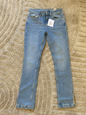 Blå raka jeans från Bik Bok  - Snygga ljusblå jeans  med rak passform och klassisk femficksdesign. Jeansen har en liten slits vid benslutet och är gjorda i ett slitstarkt denimtyg. Perfekta för en avslappnad och trendig look.